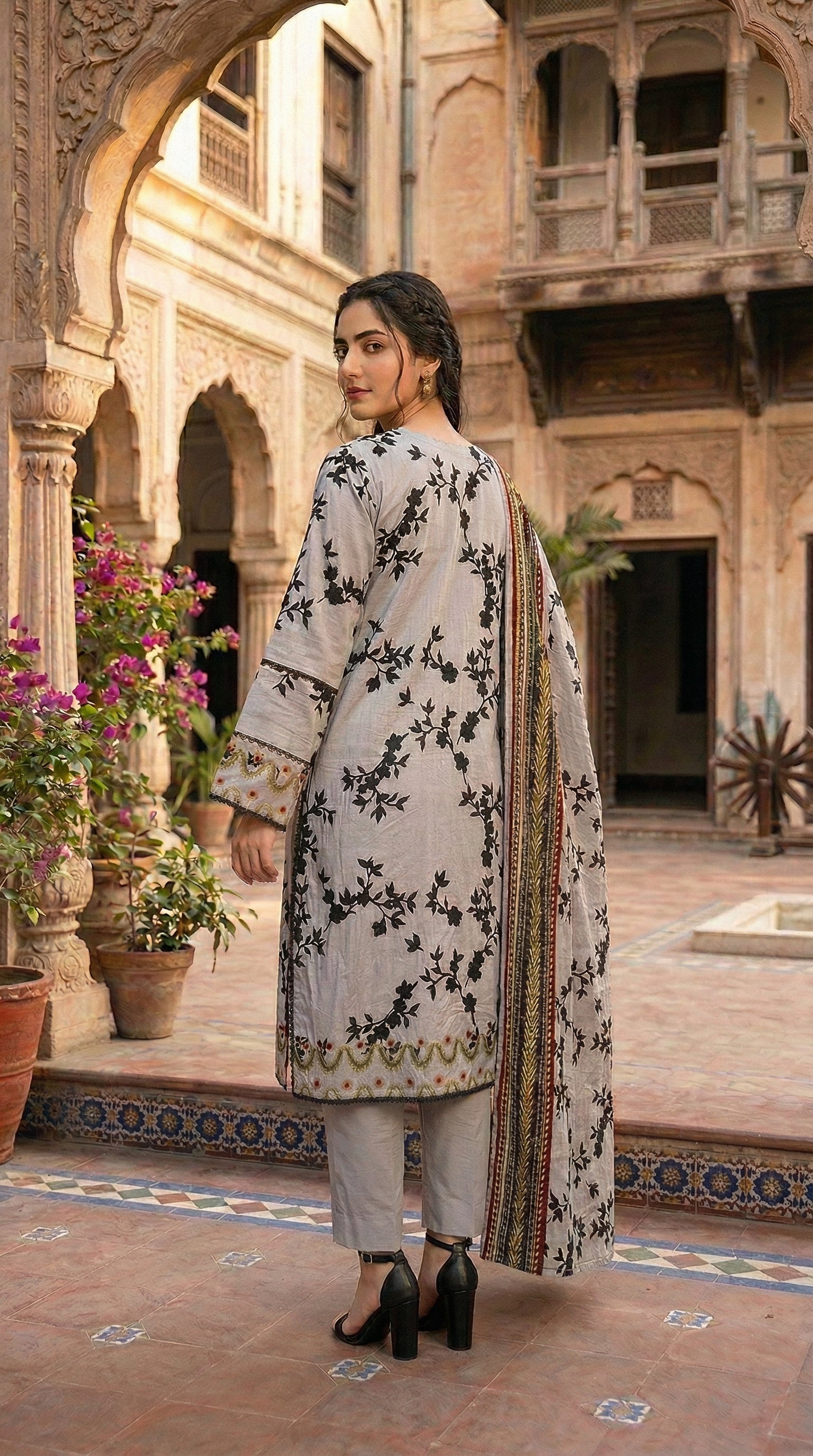 Back view of floral printed women suit with detailed border dupatta. Elegant cloudy grey floral sapphire suit for women with printed dupatta in traditional courtyard.